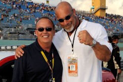 Bill Goldberg is posing with Brett Bodine at a NASCAR event.