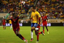 Brazil winger Philippe Coutinho (#22) competes for the ball against two Haiti defenders.