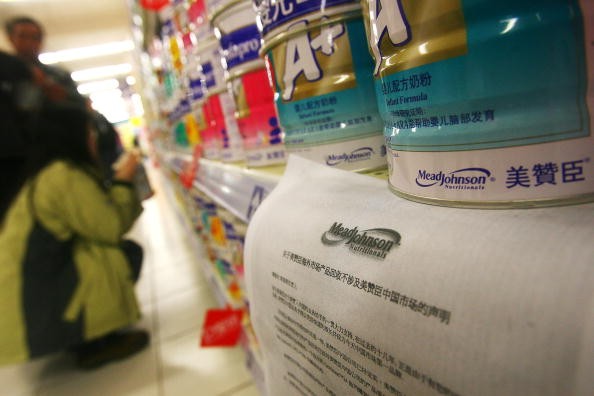 Customers buy milk powder in front of Mead Johnson milk powder products, where an announcement reading 'the callback of overseas Mead Johnson products will not involve the Chinese market' is placed, at a supermarket on February 25, 2006 in Ningbo of Zheji