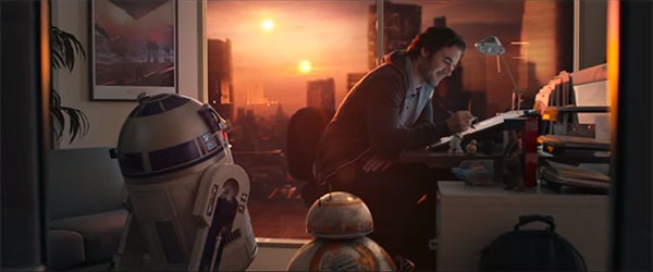 A digital artist working on his "Star Wars" game project, while R2D2 and BB-8 watches over him.