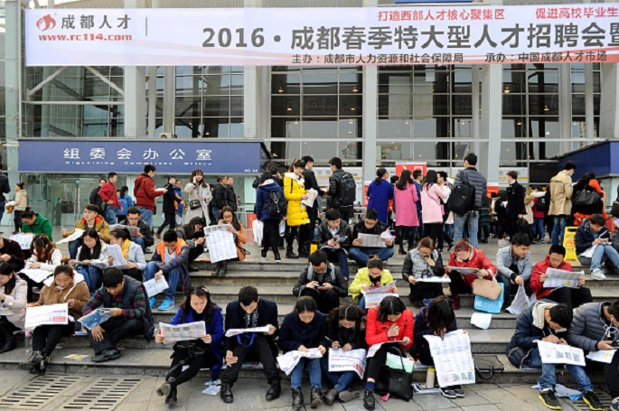 Take it sitting down: Job hunters turn to the traditional way of looking for work as they scan papers in front of a labor market on Feb. 27, 2016, in Chengdu, Sichuan Province.