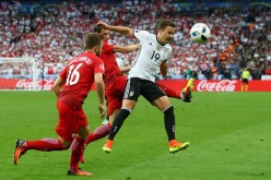 Germany striker Mario Götze (#19) competes for the ball against two Poland defenders.