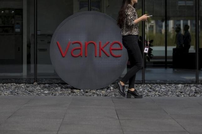 An employee walks past a logo of Vanke at its headquarters in Shenzhen, south China's Guangdong Province, Nov. 2, 2015.