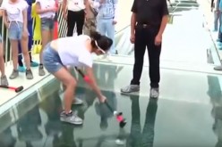 A tourist tries to smash the glass panel on a glass-bottom bridge in China