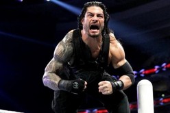 Roman Reigns flexes his muscles before a wrestling match.