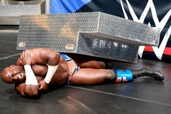 Apollo Crews cringes in pain after Sheamus hits him with the steel steps.