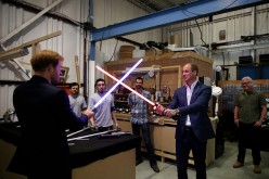 Prince Harry (L) and Prince William, Duke of Cambridge, try out light sabres during a tour of the Star Wars sets at Pinewood studios on April 19, 2016 in Iver Heath, England. 