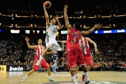 Real Madrid shooting guard Rudy Fernandez (in white) passes off against three Olympiacos Piraeus defenders.