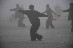 Notwithstanding the smog enveloping the area, people do their rounds of exercise on the street at Runan County of Zhumadian in Henan Province on Dec. 23, 2015.