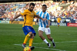 Barcelona winger Arda Turan (L) competes for the ball against Malaga's Roberto Rosales.