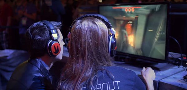 Two event goers try out the multiplayer shooter video game "Evolve" on PC.