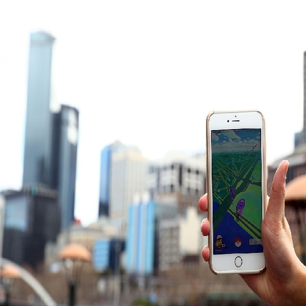 A man holds up his phone as he plays the Pokemon Go game on July 13, 2016 in Melbourne, Australia. The augmented reality app requires players to look for Pokemon in their immediate surroundings with the use of GPS and internet services turning the whole w
