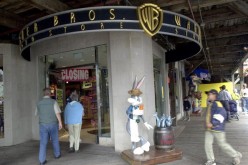 People walk by a statue of cartoon character Bugs Bunny, dressed as a fisherman, outside of a Warner Bros. Studio Store.