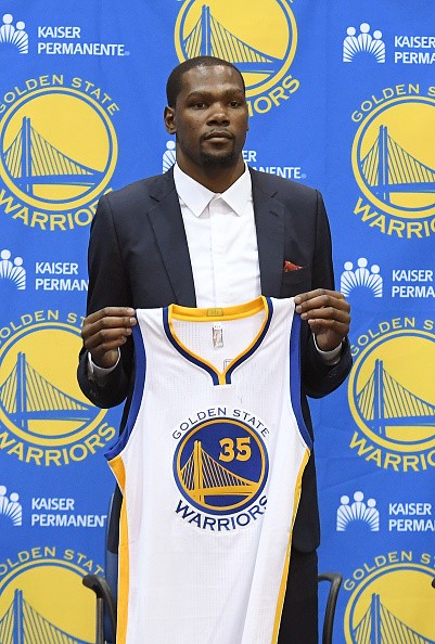 Kevin Durant holds his new Golden State Warriors jersey during his introductory press conference