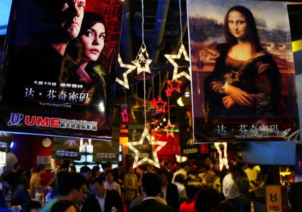People walk below movie posters at the Xintiandi entertainment center on May 18, 2006, in Shanghai, China.
