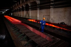A worker walks past a hot roller steel at a steel manufacturing plant in Changzhou, Jiangsu Province.