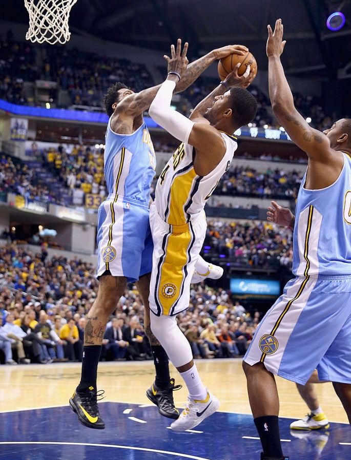 Indiana Pacers forward Paul George (middle) was blocked by a Denver Nuggets defender.