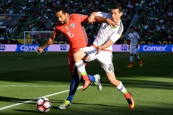 Mexico striker Hirving Lozano (R) competes for the ball against Chile's Jean Beausejour.