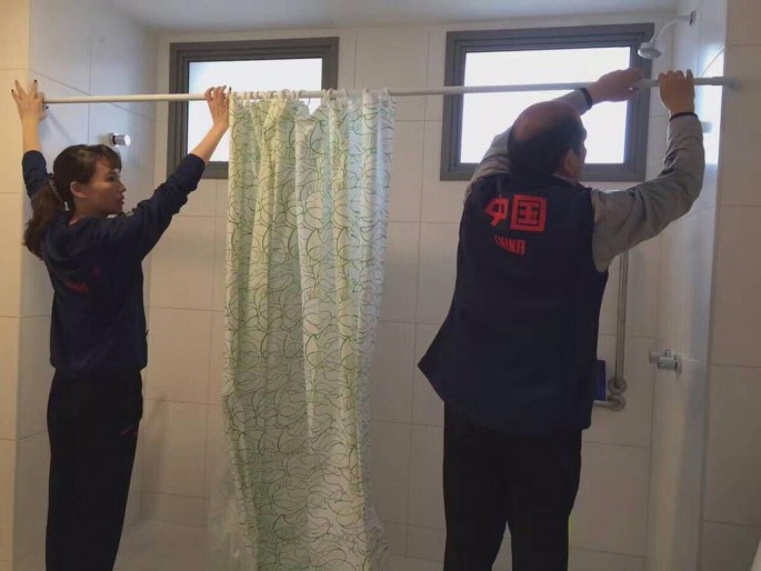 Members of the Chinese gymnastics team putting the shower curtains in their quarters at the Olympic Village in Rio. 