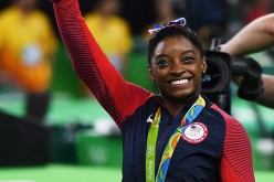 Simone Biles of the United States waves to fans with her gold medal after the medal ceremony for the Artistic Gymnastics Women's Team on Day 4 of the Rio 2016 Olympic Games.