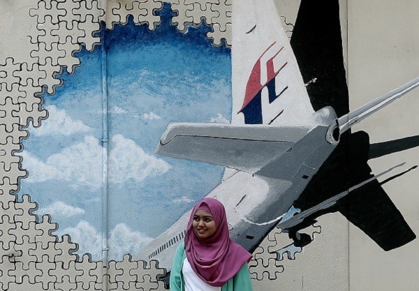 A Malaysian woman poses in front of a mural of missing Malaysia Airlines MH370 plane in a back-alley in Shah Alam in Malaysia.