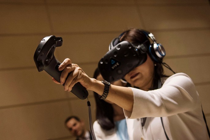 A visitor tries a special headset and trackpad made by American HTC company to experience virtual reality during the 2016 Tianjin World Economic Forum.