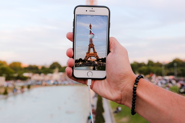 A man catches a Pokemon in a Pokeball, while playing Nintendo Co.'s Pokemon Go augmented-reality game at the Trocadero, in front of the Eiffel tower, on August 17, 2016 in Paris, France.