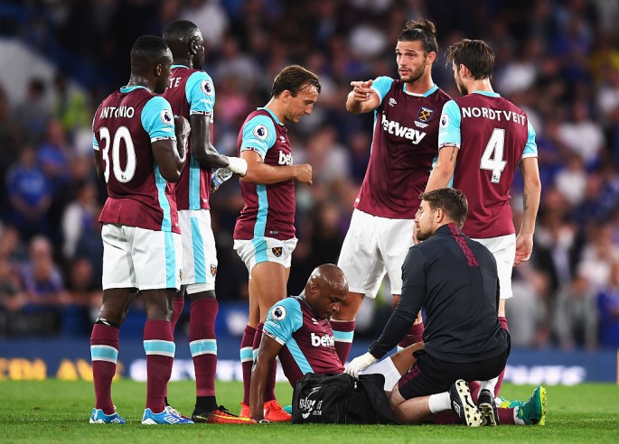 West Ham players gather around new-signing Andre Ayew (sitting) after the forward suffered a thigh injury in their match against Chelsea.