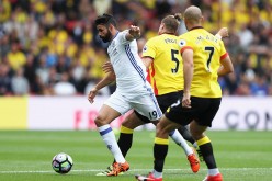 Chelsea striker Diego Costa (#19) competes for the ball against two Watford defenders.