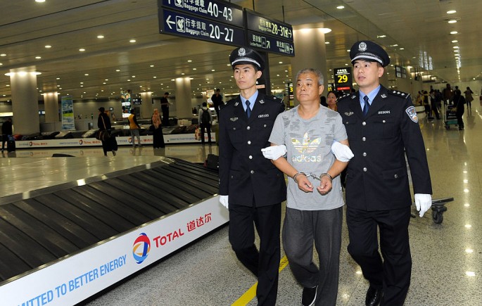 Police escort an economic crime suspect accused of misusing public money at Pudong Airport in Shanghai.