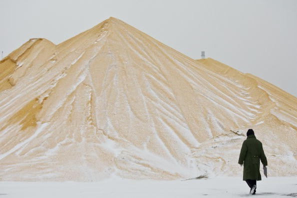A farmer walks past a pile of corn at a state grain reserves depot on Dec. 19, 2008, in Yushu in Jilin Province, China.