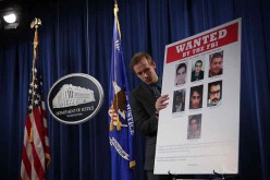 A Department of Justice employee put up a poster of indicted hackers in Washington on March 24, 2016