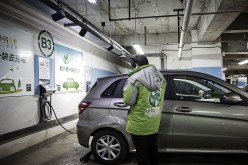 An attendant waits as an electric car is being powered in a charging station in Beijing.