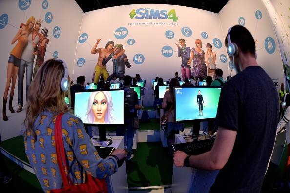 Visitors try out the game 'Sims 4' at the Electronic Arts stand at the 2014 Gamescom gaming trade fair on August 14, 2014 in Cologne, Germany.