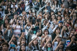 South Korean K-Pop fans try to catch a glimpse of boy bands arriving in the parking lot on June 18, 2016 in Suwon, South Korea. 