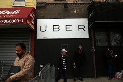Men stand in front of a Uber sign as drivers protest the company's recent fare cuts and go on strike in front of the car service's New York offices.