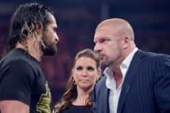 Triple H stares at Seth Rollins with Stephanie McMahon looking on. 