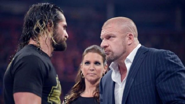 Triple H stares at Seth Rollins with Stephanie McMahon looking on. 