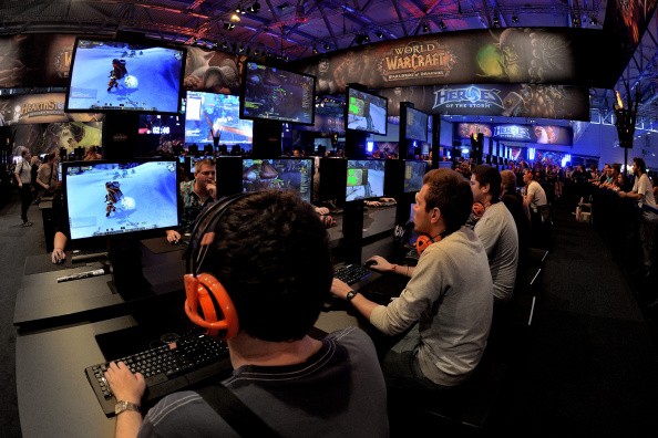 Visitors try out the massively multiplayer online role-playing game 'World Of Warcraft' at the Blizzard Entertainment stand at the 2014 Gamescom gaming trade fair.