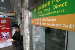 A man emerges from a post office where a Postal Savings Bank of China branch offers remittance service.
