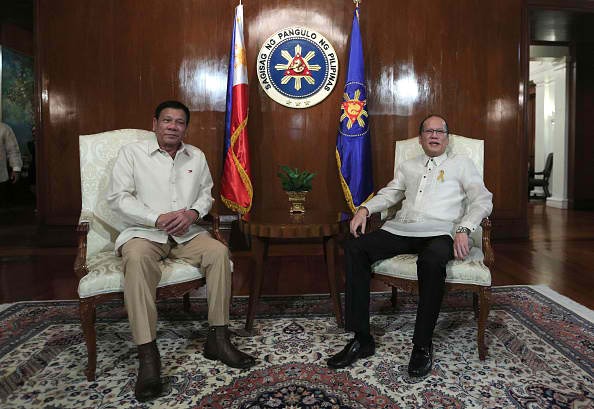 Philippine President Rodrigo Duterte sits beside former President Benigno Aquino Jr.
