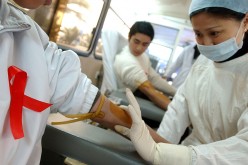 A nurse prepares to collect blood from a donor during a volunteer blood donation campaign to mark World AIDS Day.