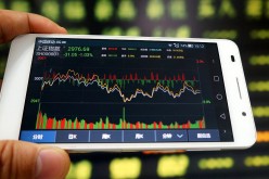 An investor uses a mobile phone to look at stock information in a stock market in Huaibei, Anhui Province.