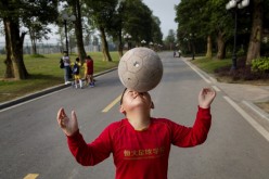 A young Chinese student balances the ball on his nose as he walks to a training match at the Evergrande International Football School on June 14, 2014, near Qingyuan in Guangdong Province, China.