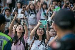 South Korean K-Pop fans try to catch a glimpse of boy bands arriving in the parking lot amid police presence on June 18, 2016 in Suwon, South Korea.  