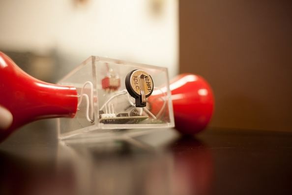 Researchers modified a hand-crank flashlight by installing a small supercapacitor (in the center) in a conventional button battery case. The light continued to glow long after the cranking stopped, th