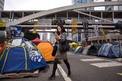 A businesswoman walks past tents used by pro-democracy protesters at the Admiralty protest site on Nov. 13, 2014 in Hong Kong, Hong Kong. 