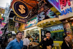 Pedestrians walk past a money exchange booth in Hong Kong.
