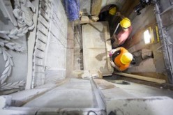 Workers remove a marble slab covering the original stone burial bed where Jesus Christ is said to have been laid to rest after being crucified. A layer of loose fill material is seen beneath.