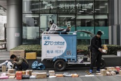 Delivery personnel sort out parcels beside a ZTO Express Delivery vehicle in Beijing.